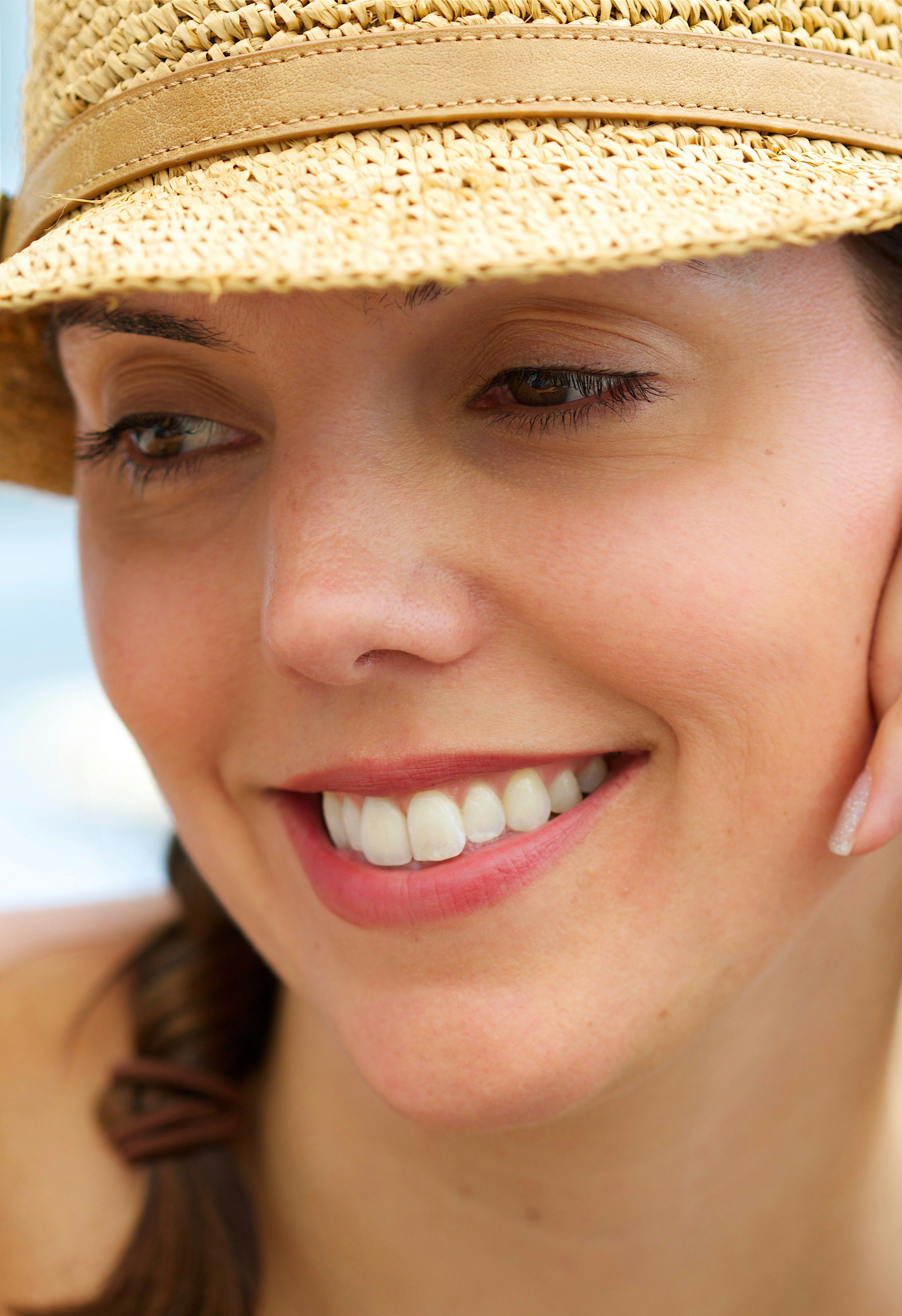 a woman wearing a straw hat talking on a cell phone