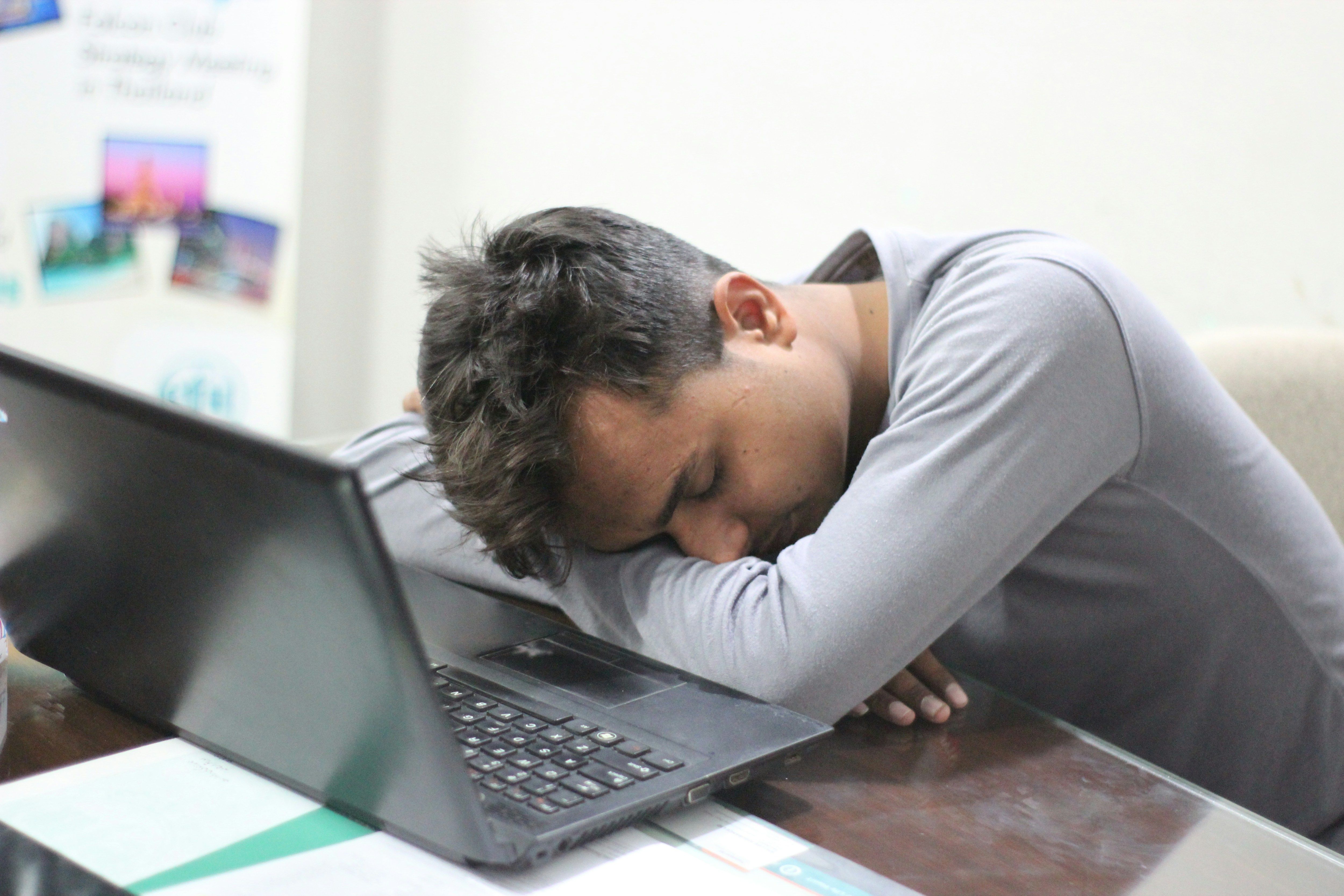 un hombre durmiendo en su portátil en un escritorio